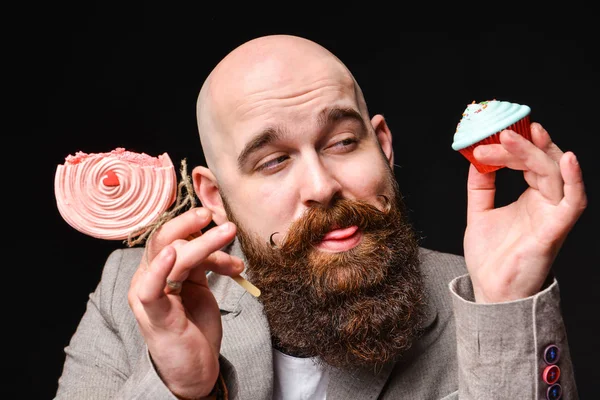 Gelukkige baard kale man met twee room cakes op zwarte achtergrond. — Stockfoto