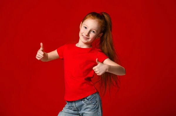 Tiener meisje met gezonde sproeten huid, het dragen van een rood t-shirt, kijkend naar de camera toont grote duimen omhoog, happy Facial Expression — Stockfoto