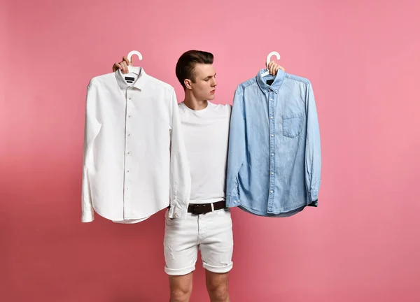 Genç adam bir gömlek seçiyor. Mavi mi beyaz mı? Ne seçimi??