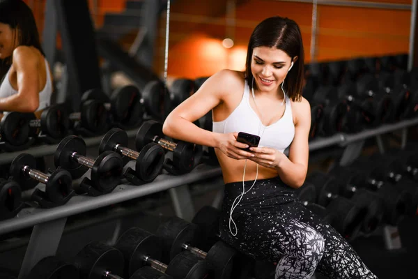 Retrato de una joven deportista con smartphone escuchando música en el gimnasio. — Foto de Stock