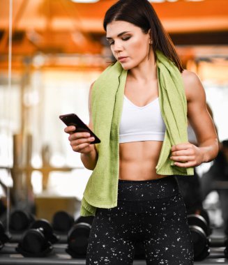 Genç kadın spor salonunda smartphone kullanarak yerleştirmek