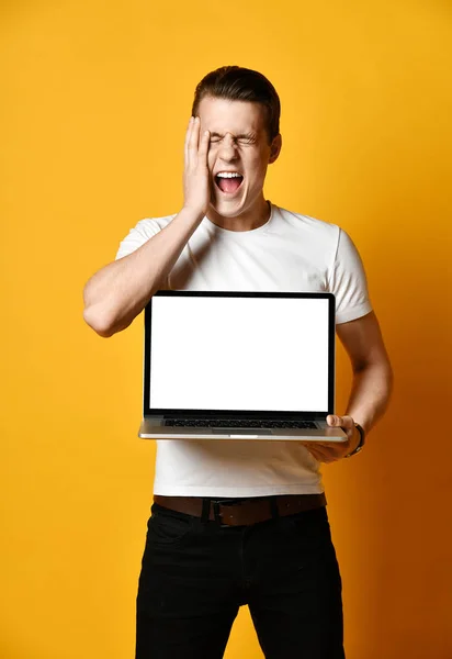 Un joven guapo sosteniendo y mostrando la pantalla de un portátil — Foto de Stock