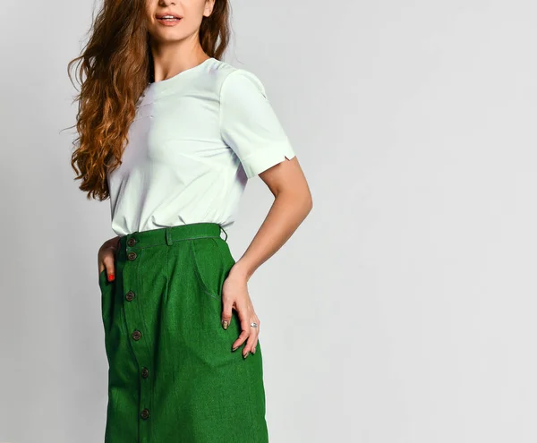 Young brunette girl with long hair in a white tank top and a green skirt. on a light background — 스톡 사진