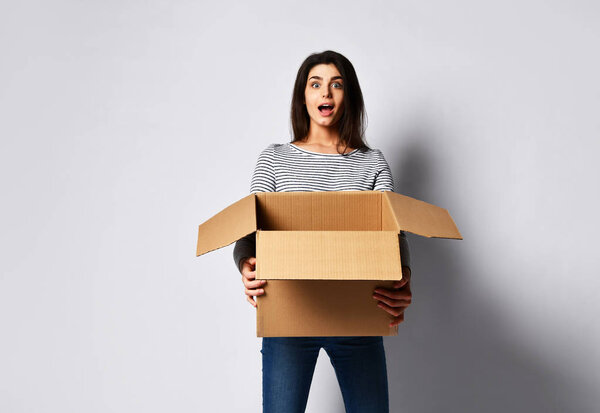 beautiful brunette woman standing on a light background with a moving cardboard box