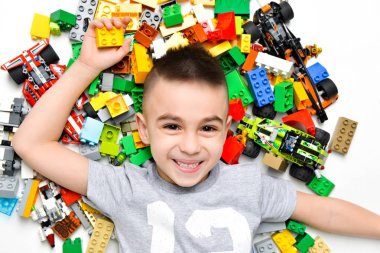 Küçük çocuk içeride bir sürü renkli plastik oyuncakla oynuyor.