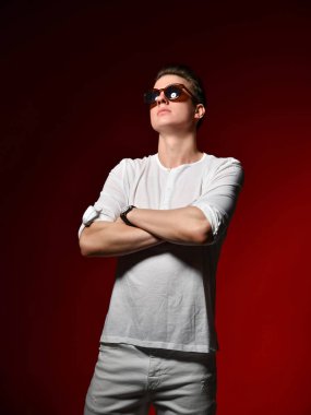 Zarif rahat elbise ve güneş gözlüğü kırmızı bir arka plan üzerinde stüdyoda Zarif genç yakışıklı adam.
