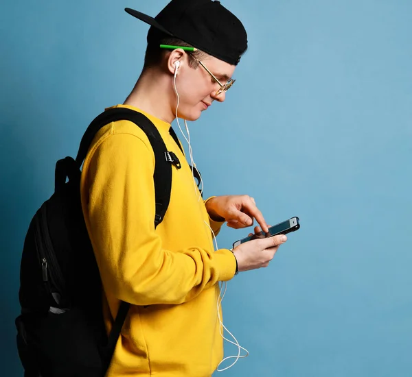 Retrato de um estudante alegre usando mochila, em boné e chalupa — Fotografia de Stock