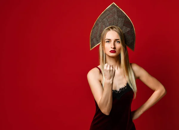 Irritado bela jovem mulher em chapéu kokoshnik mostra punho na câmera, ameaças alguém vestido com vestido de veludo, isolado sobre fundo vermelho, — Fotografia de Stock