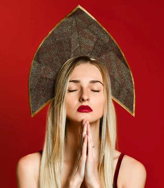 Giovane bella donna caucasica in berretto kokoshnik pregare con le mani insieme chiedendo qualcosa o — Foto Stock