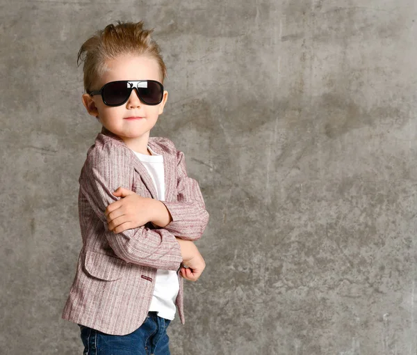 Neşeli, heyecanlı küçük bir çocuğun beton duvarın üzerinde tek başına duruşu.. — Stok fotoğraf