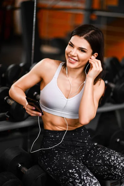Retrato de una joven deportista con smartphone escuchando música en el gimnasio. — Foto de Stock