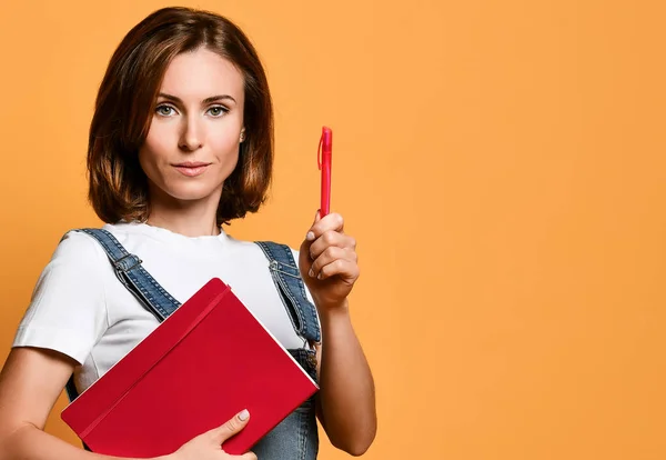 Pretty young beautiful woman standing, take notes, holding textbook notebook organizer in hand and pen — Stock Photo, Image