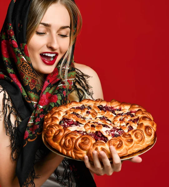 Portrait of a young beautiful blonde in headscarf holding a delicious homemade cherry pie. — Stock Photo, Image