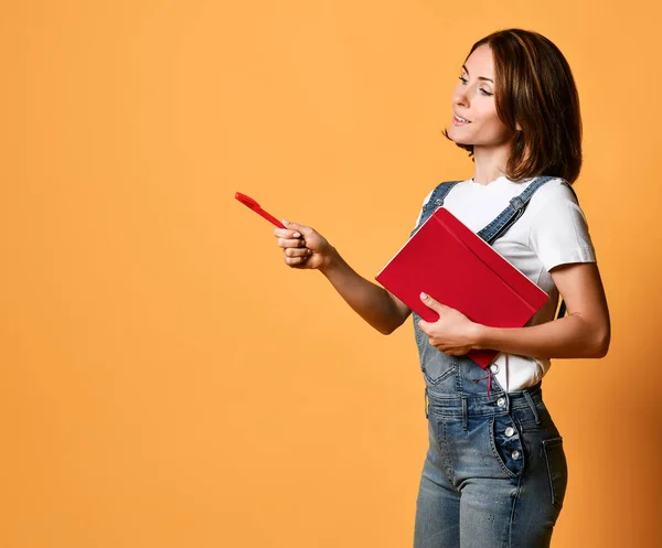 Pretty young beautiful woman standing, writing, take notes, holding textbook notebook organizer in hand and pen — Stock Photo, Image