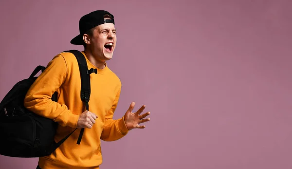 Joven estudiante alegre con una mochila se ejecuta aislado en el estudio sobre un fondo púrpura — Foto de Stock