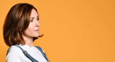 Beyaz bir t-shirt ve kot genç bir güzel esmer Portresi, sarı bir arka plan üzerinde yan bakıyor