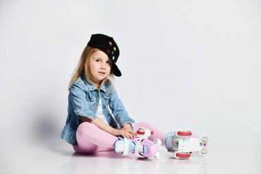 kız mavi bir kot ve kap içinde silindirler üzerinde oturur ve gülümsüyor. Çocuklar için yaz sporları.