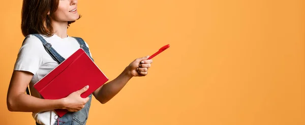 Pretty young beautiful woman standing, writing, take notes, holding textbook notebook organizer in hand and pen — Stock Photo, Image