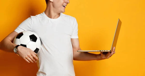 Dizüstü bilgisayarı ve futbol topu olan genç bir adam. — Stok fotoğraf
