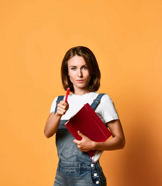 Pretty young beautiful woman standing, take notes, holding textbook notebook organizer in hand and pen — Stock Photo, Image