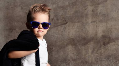 Sevimli şık çocuk beton duvarın yanında sandalyede oturan