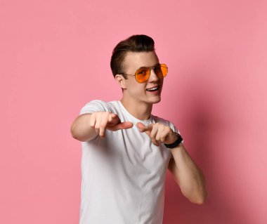 Beyaz bir t-shirt size onun işaret eden bir şık, esmer, sevimli, pozitif adam Portresi