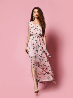 İnce kıvırcık kadın modeli ipek soluk pembe elbise tam büyüme kamera bakıyor. Romantik giysiler içinde sevimli kız bir tarih gidiyor