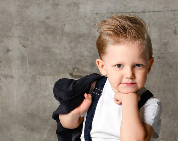 Sevimli şık çocuk beton duvarın yanında sandalyede oturan