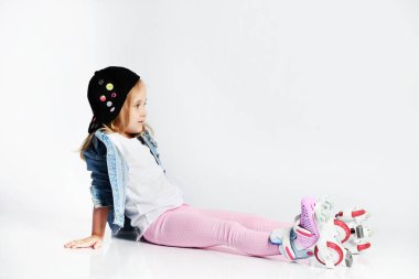 kız mavi bir kot ve kap içinde silindirler üzerinde oturur ve gülümsüyor. Çocuklar için yaz sporları.