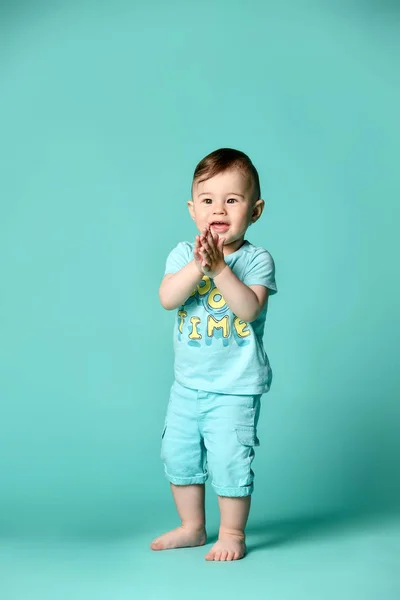 Full length portrait of a toddler boy in a blue summer cotton suit isolated in a turquoise background. — Stock Photo, Image