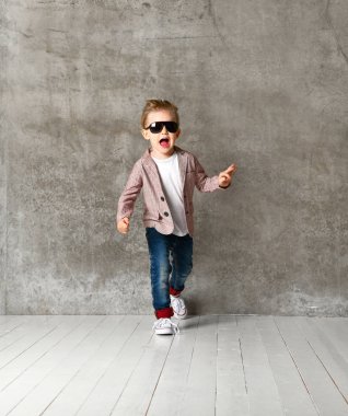 Neşeli, heyecanlı küçük bir çocuğun beton duvarın üzerinde tek başına duruşu..
