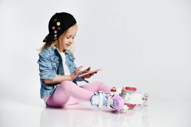 kız mavi bir kot ve kap içinde silindirler üzerinde oturur ve gülümsüyor. Çocuklar için yaz sporları.