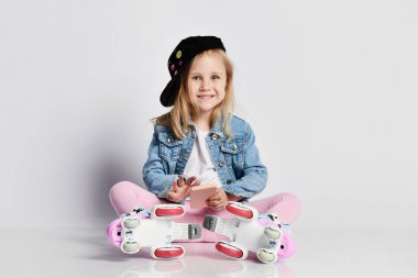 kız mavi bir kot ve kap içinde silindirler üzerinde oturur ve gülümsüyor. Çocuklar için yaz sporları.