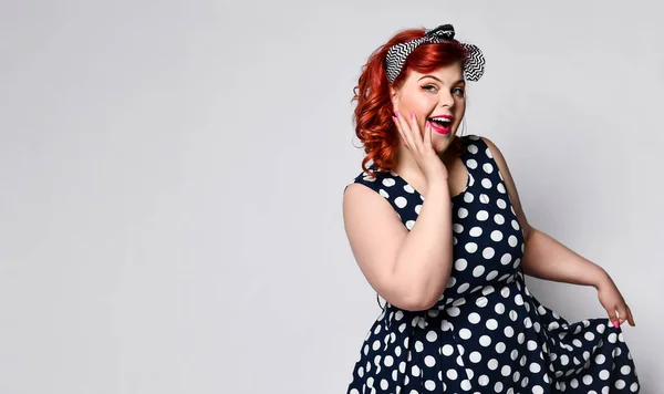 Pin up a female portrait. Beautiful retro fat woman in polka dot dress with red lips and manicure nails and old-style haircut