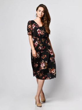 İnce kıvırcık kadın modeli ipek bir elbise tam büyüme kamera bakıyor. Romantik giysiler içinde sevimli kız bir tarih gidiyor