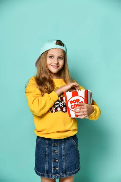 Jonge schattige vrouw die popcorn op groene achtergrond eet. — Stockfoto