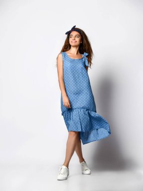 İnce kıvırcık kadın modeli ipek soluk mavi elbise tam büyüme kamera bakıyor. Romantik giysiler içinde sevimli kız bir tarih gidiyor