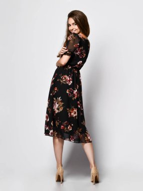 İnce kıvırcık kadın modeli ipek bir elbise tam büyüme kamera bakıyor. Romantik giysiler içinde sevimli kız bir tarih gidiyor