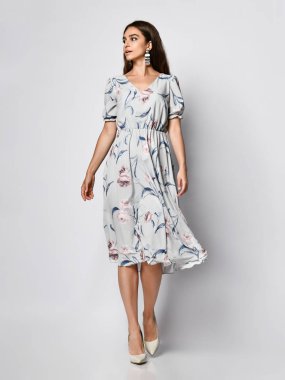 İnce kıvırcık kadın modeli ipek soluk pembe elbise tam büyüme kamera bakıyor. Romantik giysiler içinde sevimli kız bir tarih gidiyor