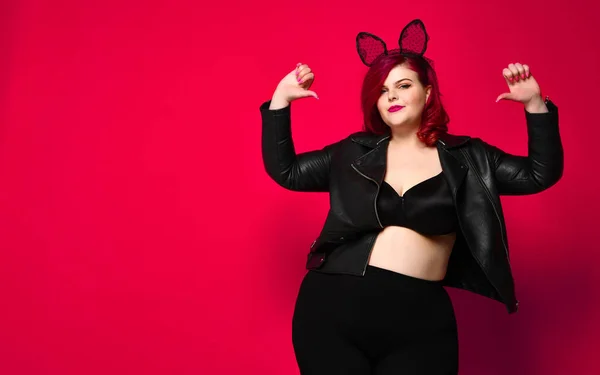 Bonito sexy plus size morena com orelhas de coelho preto em jaqueta de couro e roupa interior posando no fundo vermelho — Fotografia de Stock