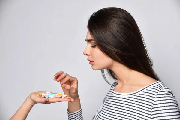 Jovem morena menina escolhe qual pílula para beber daqueles oferecidos em sua mão — Fotografia de Stock