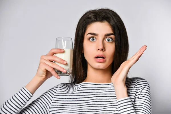 Retrato de una joven sorprendida con un vaso de leche en la mano — Foto de Stock