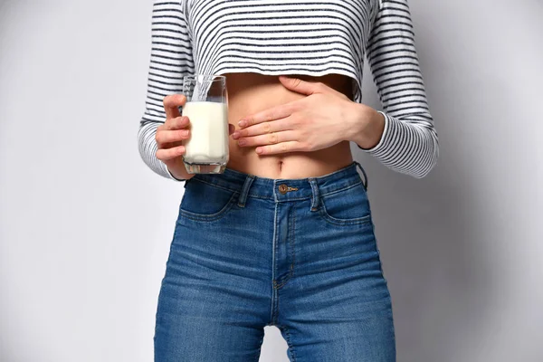 Ausgeschnittenes Foto einer Frau, die ein Glas Milch in ihren Händen hält. Das Mädchen zeigt auf ihrem Bauch, das Gefühl nach einem Drink — Stockfoto