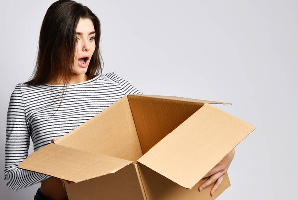 beautiful brunette woman standing on a light background with a moving cardboard box