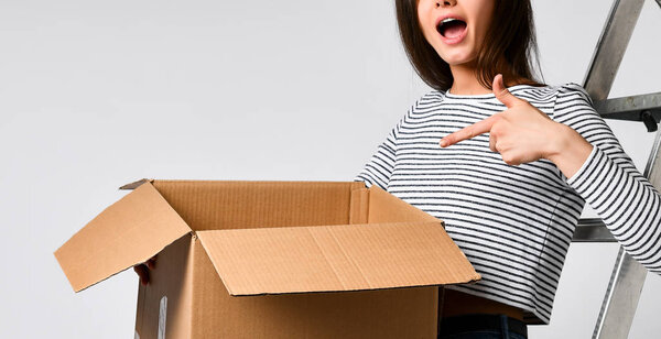 Delivery, relocation and unpacking. Smiling young woman holding cardboard box isolated on white background