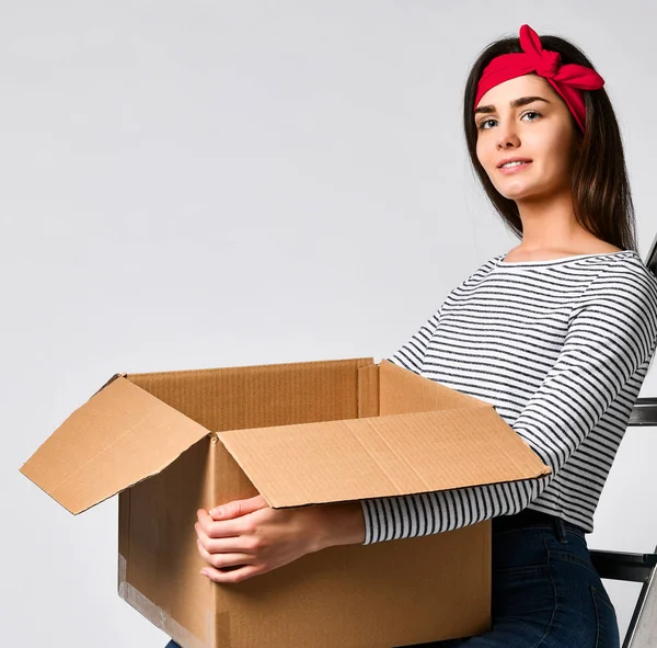 Доставка, переміщення та розпакування. усміхнена молода жінка тримає картонну коробку ізольовано на білому тлі — стокове фото