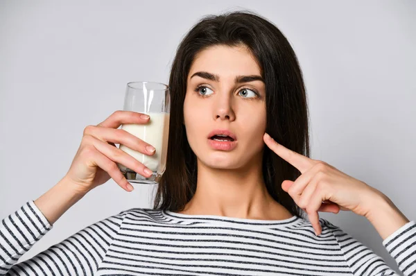 Retrato de una joven sorprendida con un vaso de leche en la mano — Foto de Stock