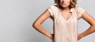 Kollarını kemerde dinlendiren, mutsuz, hafif bir arka planda izole genç, üzgün bir kızın portresi..