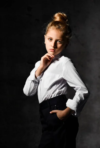 Маленька жіноча кавказька модель позує в шкільній формі на сірому бетонному студійному фоні . — стокове фото