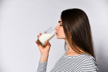 Bardaktan süt içen genç bir kızın yan portresi.